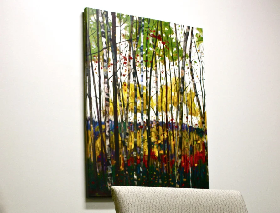 Large colourful forest painting installed above a lounge chair